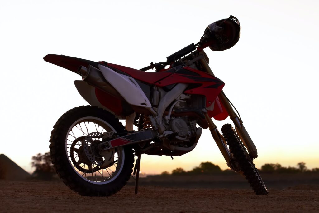 A dirt bike parked on an open plane with the sun setting in the background
